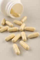 Bottle and vitamin capsules on light background, closeup