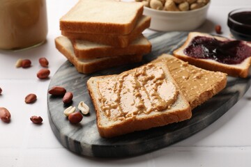 Delicious toasts with peanut butter, nuts and jam on white table