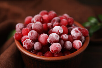 Frozen red cranberries in bowl on table, closeup