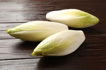 Raw ripe chicories on wooden table, closeup