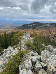 Fototapeta na wymiar Trekking in the mountains, travel in the autumn forest, landscape in the mountains, stone peak, coniferous forest, cloudy weather.