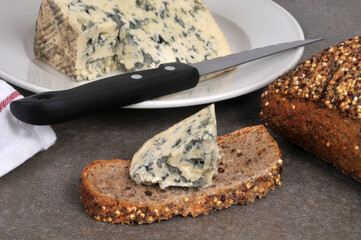 Morceau de bleu d'Auvergne sur une tranche de pain aux graines avec un couteau en gros plan
