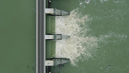 Aerial: top down view of dam releasing water, water discharge downstream