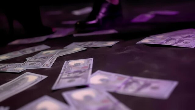 Go-go girl removes her foot in a high heeled shoe from money dollars lying on the floor during a private dance. Erotic striptease in nightclub