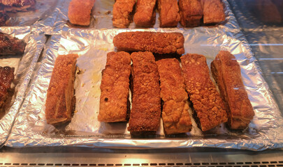 Thick slices of crispy roasted pork belly for sale on display in thermal counter in deli department of supermarket