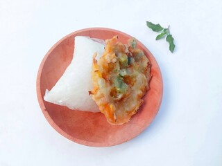 bakwan and lontong on a wooden plate on a white background. Bakwan is sliced ​​cabbage and carrots mixed with flour and then fried. lontong is rice put in plastic or banana leaves and then boiled.