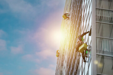 Group Industrial mountaineering workers in uniform washing exterior building glazing.