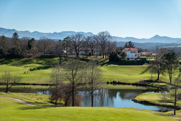 Fototapeta na wymiar Campo de golfe com um grande lago e alguns golfistas ao fundo em Arcangues no País Basco francês