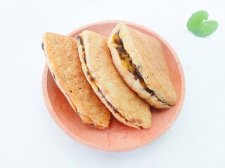 pieces of martabak filled with chocolate sprinkles on a wooden plate on a white background. martabak, traditional Indonesian sweet snack. soft bread filled with chocolate, for tea time or celebrition