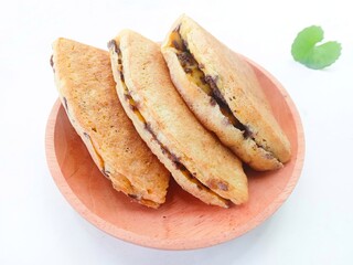pieces of martabak filled with chocolate sprinkles on a wooden plate on a white background. martabak, traditional Indonesian sweet snack. soft bread filled with chocolate, for tea time or celebrition