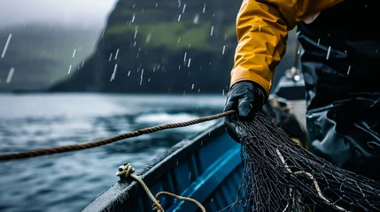 Fotobehang Close up of a Fisherman in rough weather handling nets on his boat. Concept of industrial fishing. Shallow field of view.  © henjon