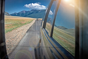 Reflection of the mountain landscape in the rear view mirror of a car. 