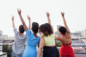 Four friends friends wave their hands and show peace symbol. Man and african women stand with their...