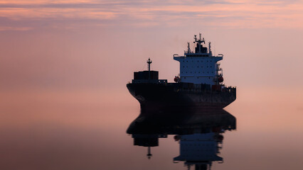 Seascape and silhouette container ship floating in sea