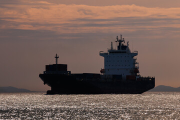 Obraz premium Seascape and silhouette container ship floating in sea