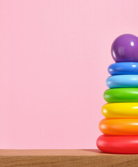 Pyramid with colored rings and round purple ball on top on a wooden table. Toys for babies. Copy space for text.