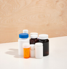 Brown, white and orange medical jars with healthy pills, supplements and vitamins on a white table.