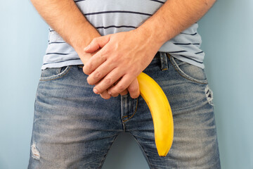 banana out of mens jeans like mens penis. potency concept - obrazy, fototapety, plakaty