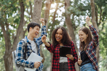 Happy group of college students use laptop feel excited overjoyed with good news over smartphone or Tablet.