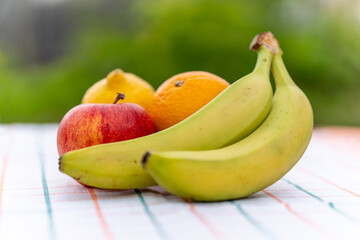 Tropical fruit mix on table with white tablecloth against a blurred background of nature. healthy food view from above