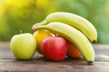 Still Life Fruits - Bananas and Apples on wooden table against a blurred background of nature .