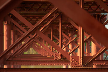 川にかかる赤い鉄橋と橋脚が生み出す幾何学模様	
