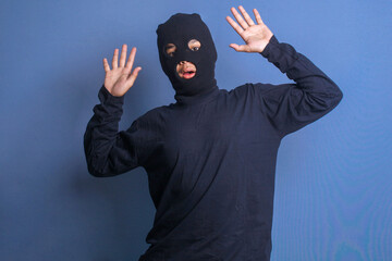 Male thief wearing black balaclava gets caught stealing and raise hands surrender