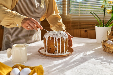 Female hands pouring icing on Easter cake. Traditional easter cake or sweet bread with topping. Easter treat. - obrazy, fototapety, plakaty