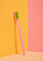 Pink toothbrush with green bristles. Dental concept.