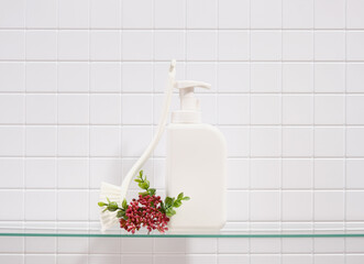 White dish detergent dispenser and a brush to clean the dirt on a white tile background.
