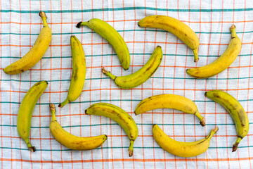 Ripe, appetizing, healthy, large, sweet bananas, neatly lined on checkered tablecloth table on a light background. The view from the top. Healthy eating