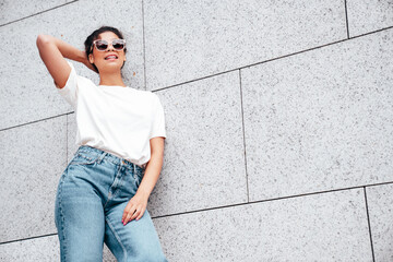 Young beautiful smiling hipster woman in trendy summer white t-shirt and jeans clothes. Carefree...