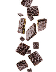 Cookies coated with chocolate and nuts fall in space. Surround light from behind. Isolated on white.