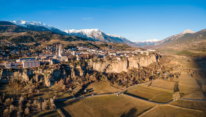 Winter panoramic view of Embrun and its famous cliff-top plateau with harvested fields in Durance...