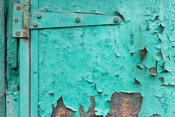 Turquoise paint cracked on the surface of an old wooden door