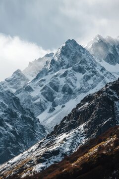 A picture of a majestic mountain range covered in snow and surrounded by clouds. This image can be used to depict the beauty of nature and the serene atmosphere of mountain landscapes