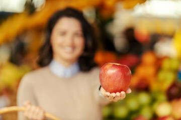 Fototapeta premium Close up of a woman holding fresh organic apple at local market.
