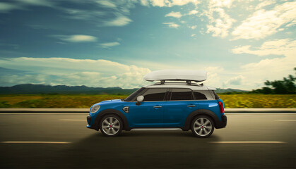 Blue SUV car with luggage box mounted on the roof. Driving on the road with motion effect. Roof box...
