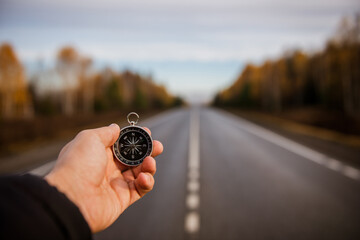 A man stands on the road and holds a compass in his hand.