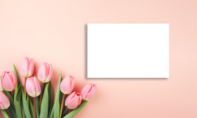 Blank invitation card with white space for mock up next to tulip flowers on peach fuzz background