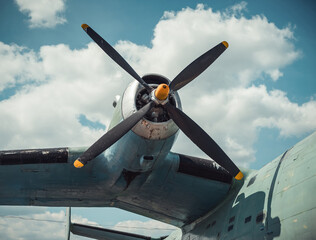 Propeller and wing of an old aircraft in front of the cloudy sky. Close-up view of teal green vintage aircraft on a sunny day.