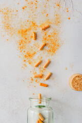 Kurkuma Kapseln verstreut auf einem grauen Tisch. Flat lay.