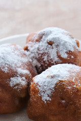 Typical dutch food commonly known as dutch doughnuts, dutchies or oliebollen with currants and powdered sugar on a white plate. Traditionally eaten on new year's eve in the Netherlands.