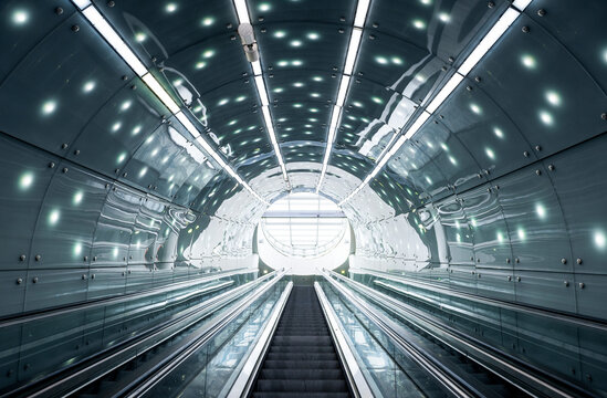 Futuristic interior: escalator moving staircase upwards inside round illuminated tunel © andrbk