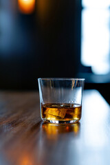 Single glass with rum on the bar top. Glass of expensive alcoholic drink with ice cube