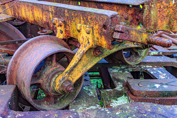 Closeup of a wheel on old train bogie, support and central axle, stacked on a huge rusty steel...