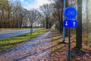Blue traffic sign indicating: Bicycle lane in both directions on side of an empty country road...