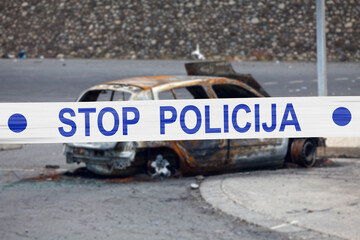 Bosnian police tape barricading a burnt car