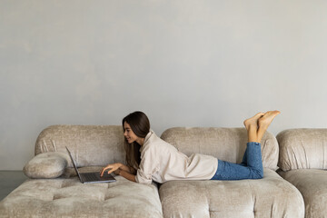 Happy smiling woman sitting on sofa, couch and using laptop at living room at home