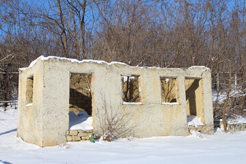 A stone building with snow on the ground and trees in the background